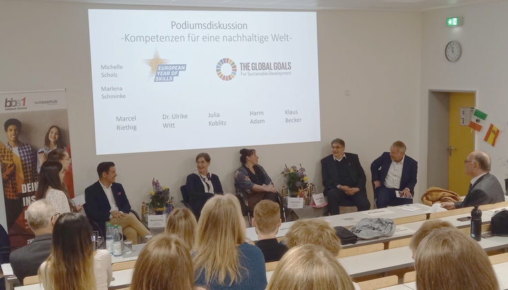 Schülerinnen und Schüler der BBS Göttingen verfolgen im Hörsaal die Podiumsdiskussion.