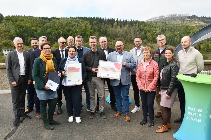 Gruppenbild mit Ministerin Melanie Walter und allen Projektteilnehmenden und -förderern bei der Bescheidübergabe auf der Staumauer der Okertalsperre.