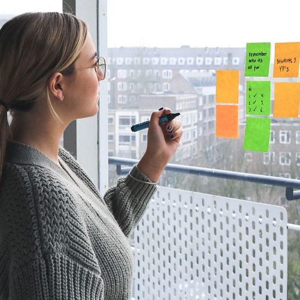 Eine Frau schreibt selbstklebende Zettel an einem Fenster.